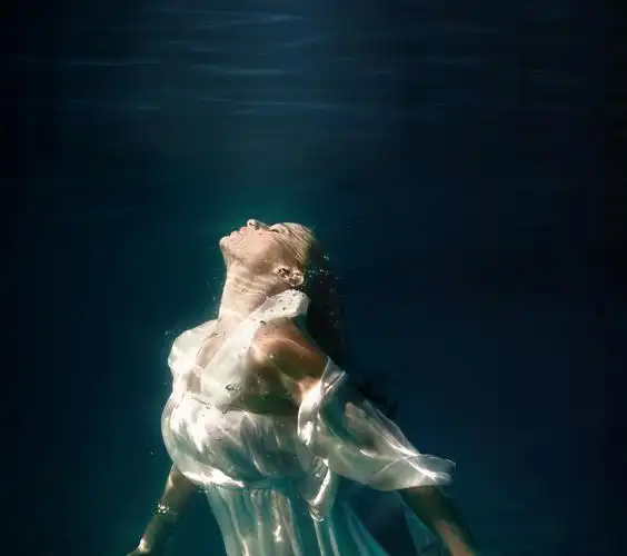 深蓝色游泳池里女孩在水下游泳