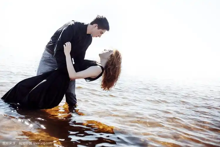 美丽的年轻夫妇拥抱站在海里,照片着色