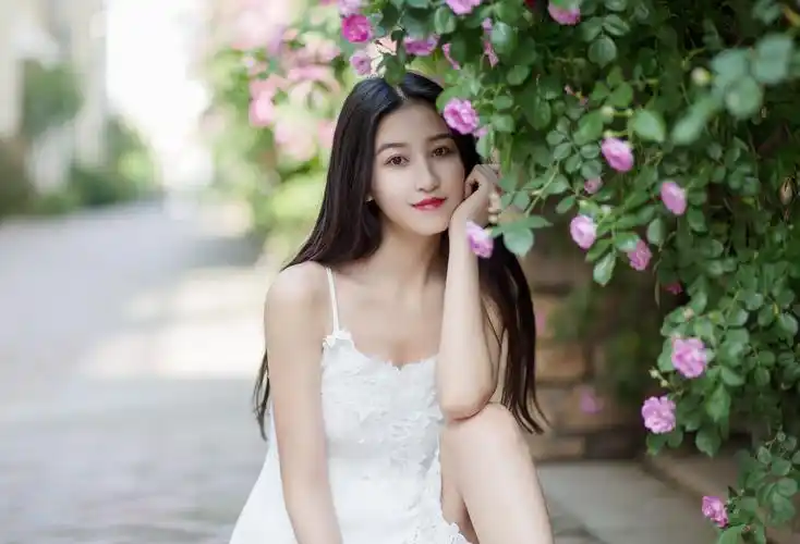 一位穿白色吊带裙的女孩,她秀发披肩,微笑迷人