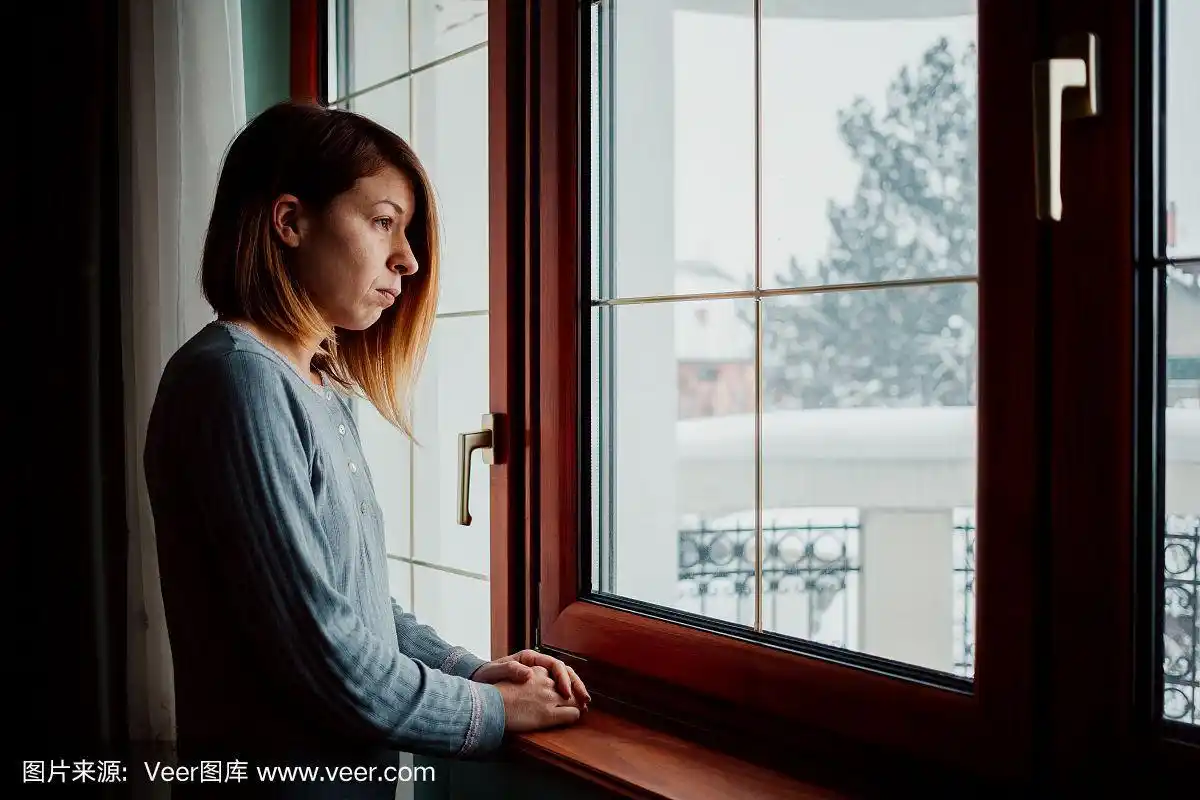 悲伤的女人坐在窗边望着外面