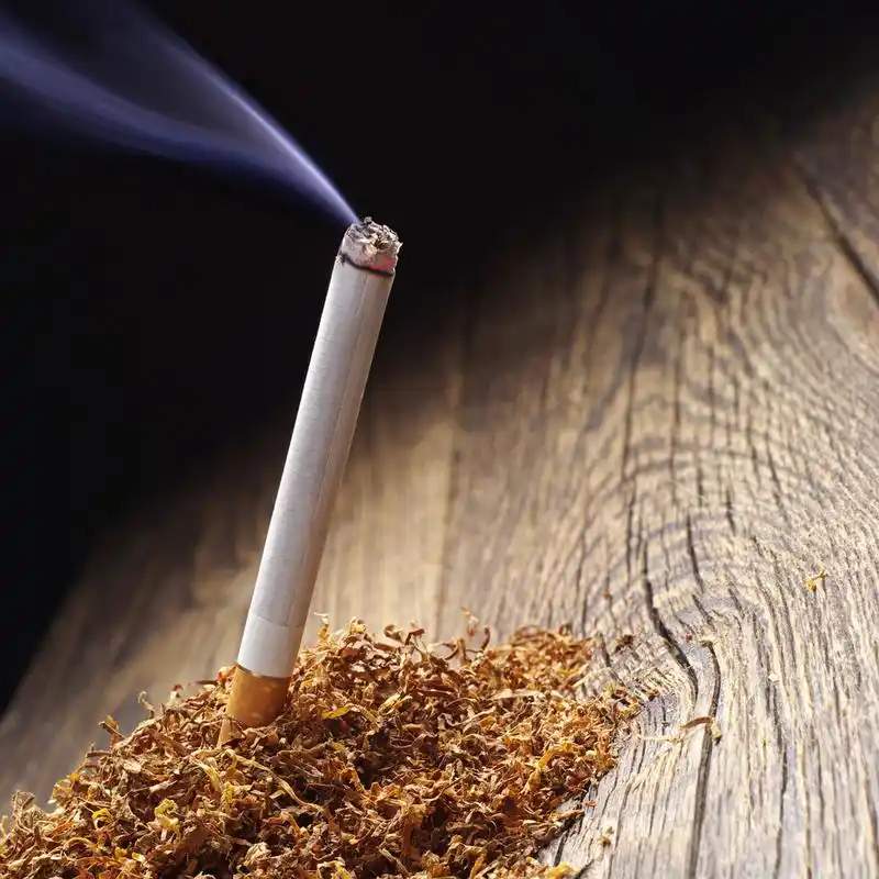 点燃一支烟和烟草,在木制的背景上点燃香烟和烟草