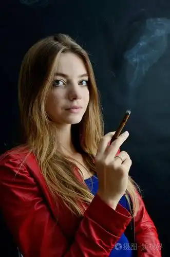 年轻的女性坐在她的手 cigarillo.穿红夹克的女人喜欢抽烟.