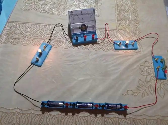 连接串联电路,并将电流表接入电路,放置在两个灯泡之间,将电流表接在