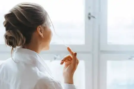 一个年轻漂亮的女人站在窗前望着外面的人.照片