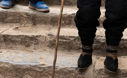 一双蹒跚的小脚在拐杖的支撑下,颤颤巍巍行走在古老的石板路上