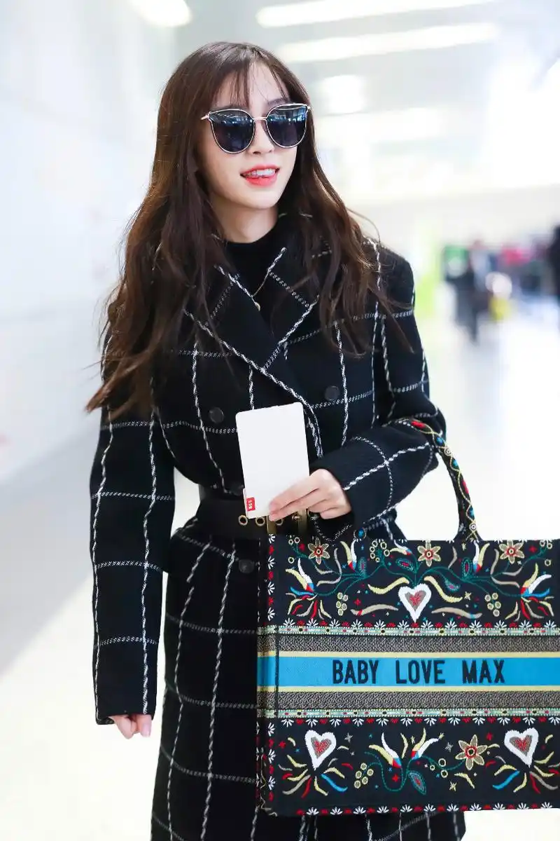 angelababy戴墨镜穿黑色格子大衣现身机场,皮肤白皙,面带微笑.