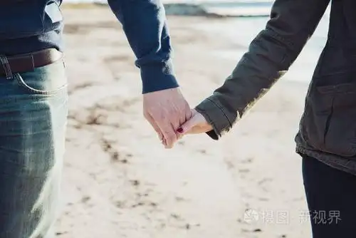 一对年轻夫妇在海边牵手