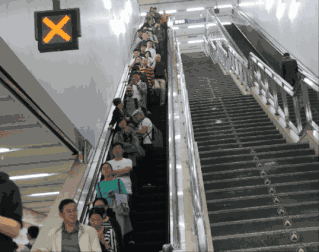 北京某地铁站内,一人在扶梯左侧行走至于长期"左行右立"会导致电梯受