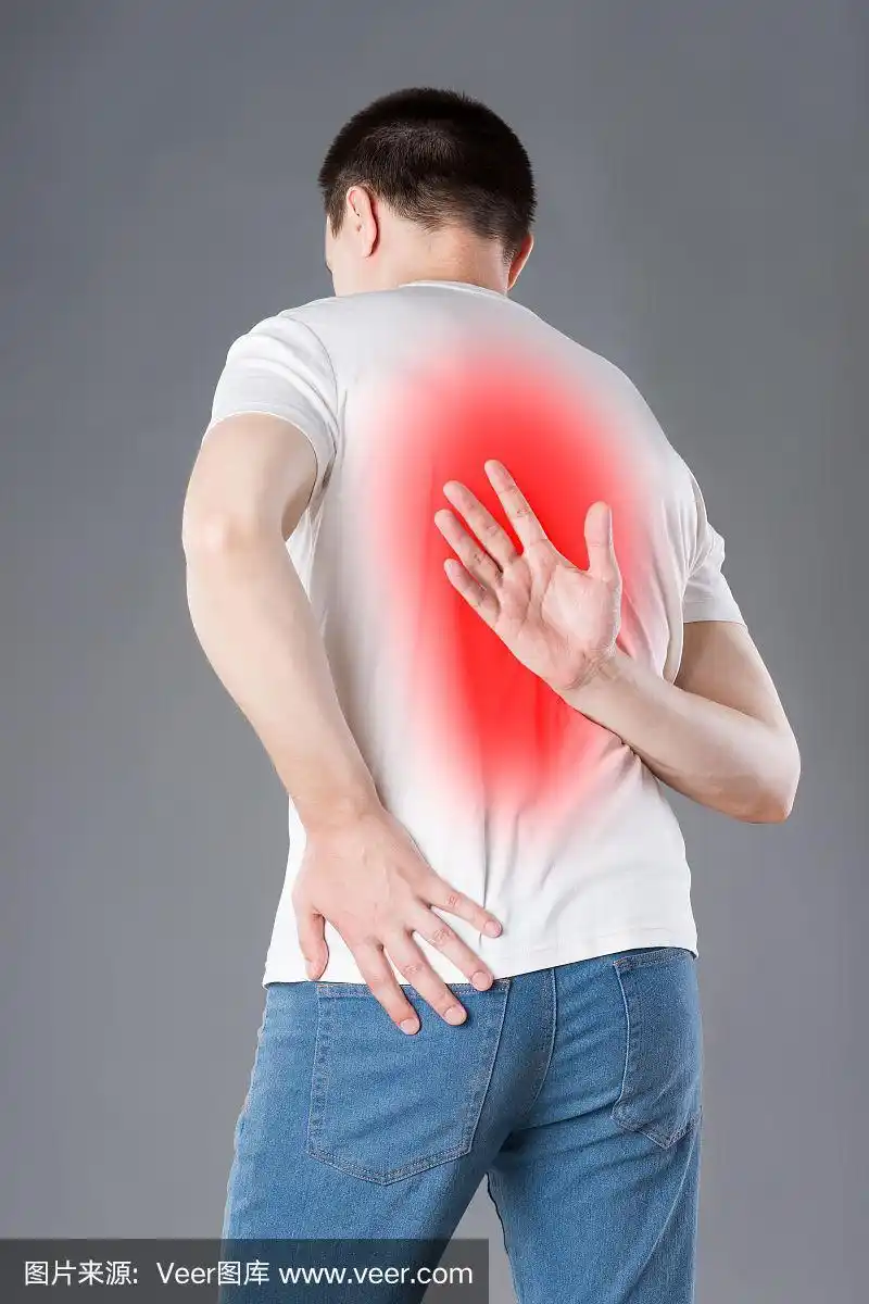 背部疼痛,在灰色背景上遭受背痛的男人