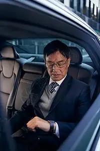公司老板坐在轿车后排看手表图片素材