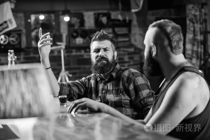 在酒吧柜台和朋友喝酒的时髦野蛮人.男人们在酒吧里喝得醉醺醺的.
