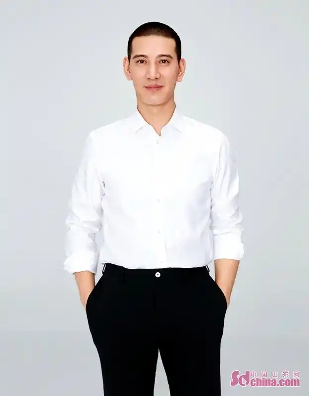 照片中蒲巴甲身着白色衬衣搭配黑色西装裤,置身于纯色背景之下,简单的