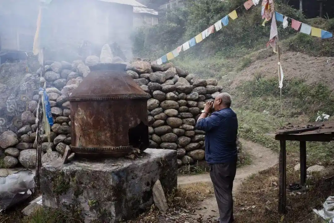 门巴族老人在火堆前吹螺号,念经前的一个仪式.