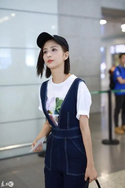 佟丽娅穿白t搭配蓝色背带牛仔裤现身机场笑容灿烂比剪刀手卖萌