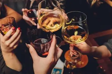 一组人在博克背景前用葡萄酒或香槟碰杯的特写镜头.老年人的手.照片