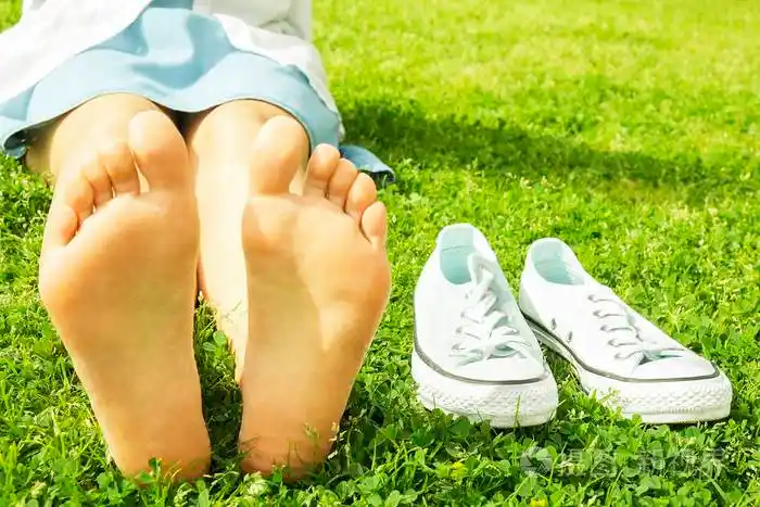 年轻女子赤脚在户外休息, 采取休息的概念.学生在大学校园围场