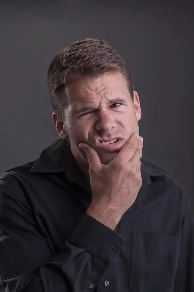 下巴疼痛,穿着黑色衬衫的白种人男子握着他的下颚,撕断或扭曲的脸上