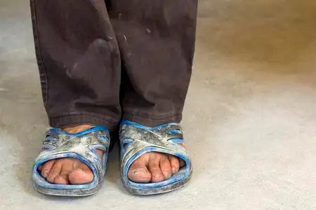 穿着旧脏衣服和鞋子的人的脚照片