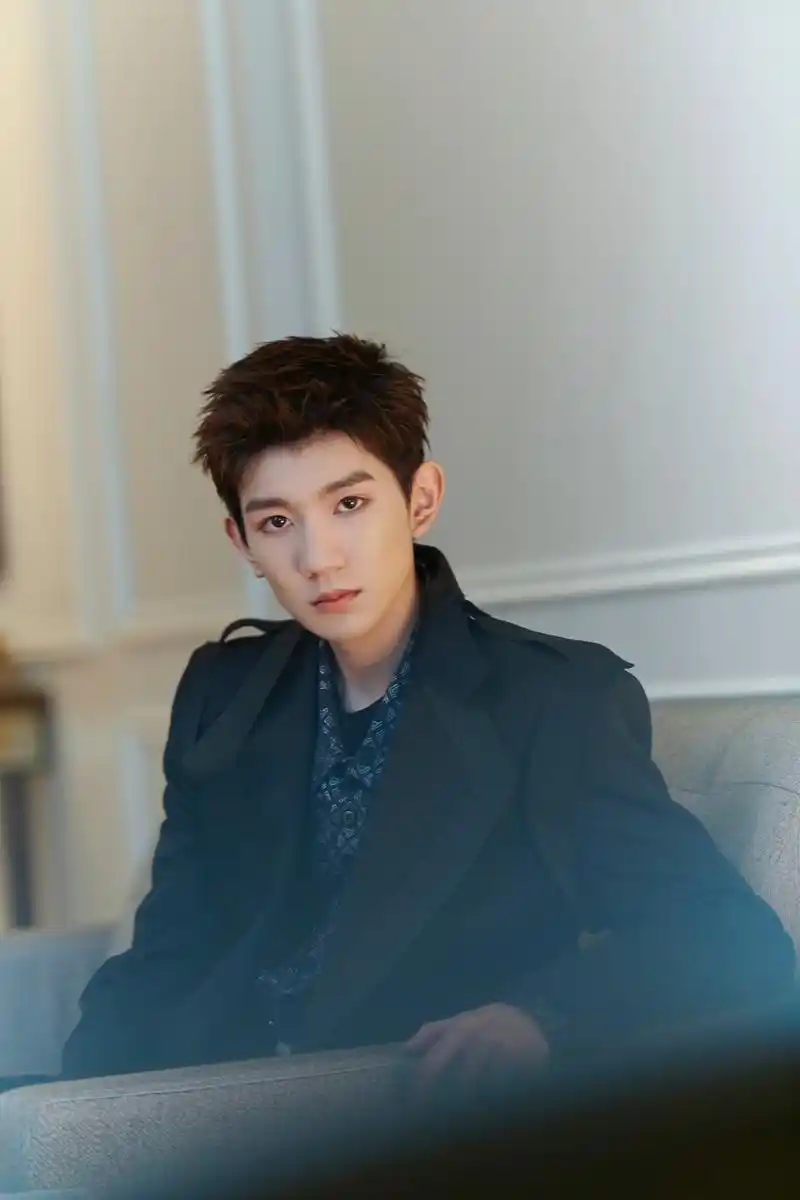 照片中王源随性坐在沙发一角直视镜头,眼神杀霸气十足