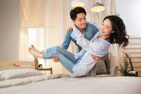 年轻丈夫把妻子抱到床上新婚夫妇坐在床上聊天幸福的情侣坐在床上的