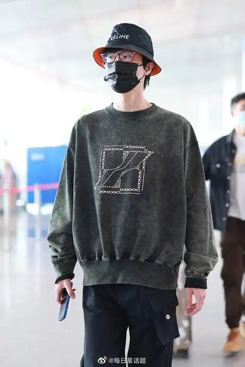 2022年4月9日,北京,许嵩穿墨绿色卫衣戴celine渔夫帽现身机场,帅气