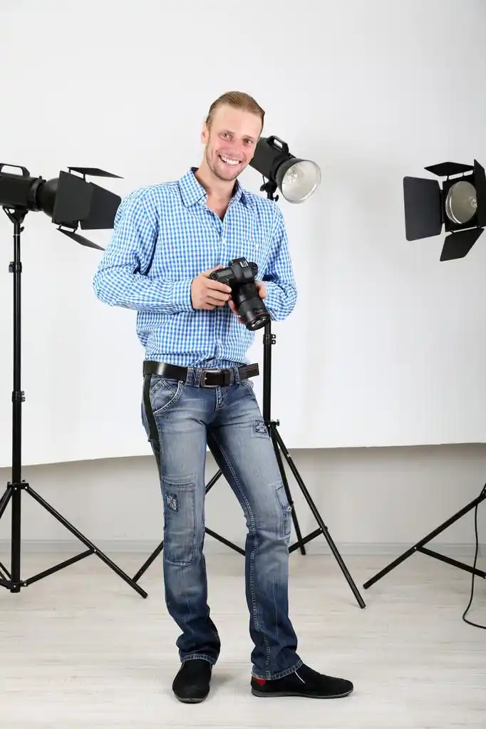 帅气摄影师用相机在工作上照片工作室背景