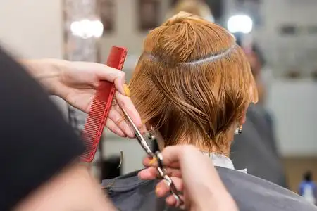 发型师剪刀换个新发型的女人.女发型师在发廊用剪刀剪头发.