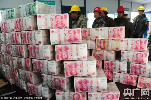 农民工在人民币码成的"小山"旁有序排队领取工资.