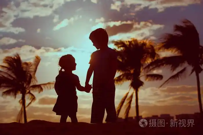 小男孩和女孩手牵着手在日落海滩