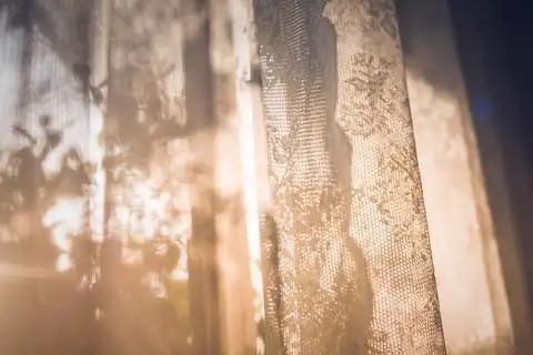 在春天的早晨,透过格子窗帘的散焦窗帘阳光夏天.绿色自然花园背景.