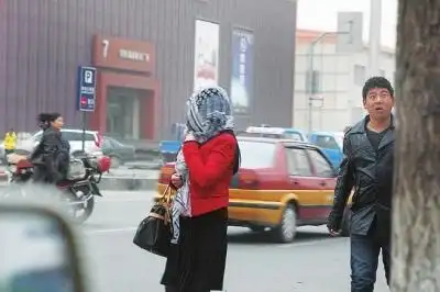 这位女士用纱巾包住了头和脸,防止沙尘的侵袭.