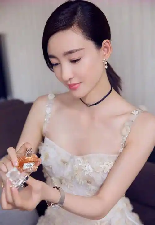 换上一袭白色抹胸衣裙,王丽坤双手拿着化妆品瓶子,露出自己白嫩的香肩