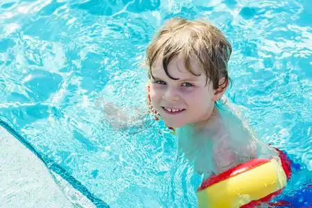 快乐的小小孩的男孩,在游泳池玩乐照片