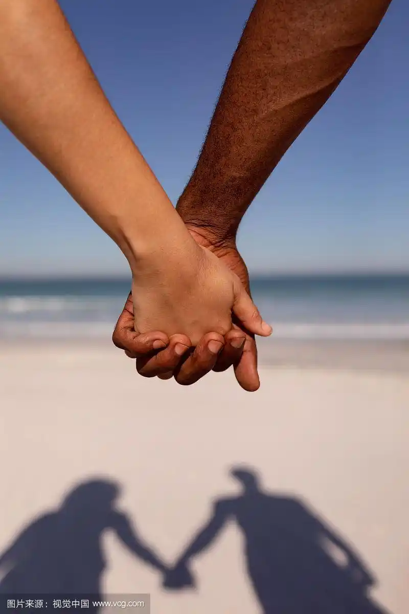 在阳光下的沙滩上牵手的情侣