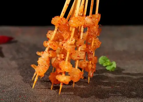 深色背景上摆放的牛筋烧烤食材肉串