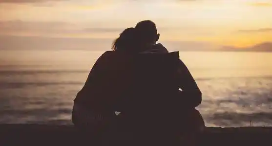 动漫情侣看太阳情侣相拥在海滩上的海边日出, 剪影两个浪漫的人拥抱和