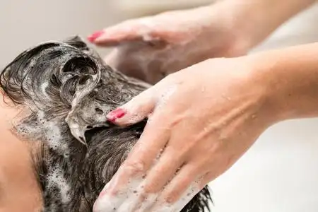 手上泡沫女性在理发店洗头.手上和头上的泡沫.特写镜头.照片