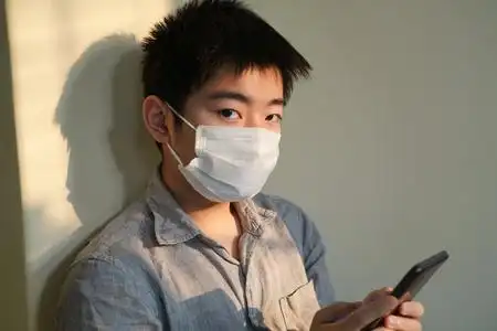 戴口罩的男孩看手机 照片