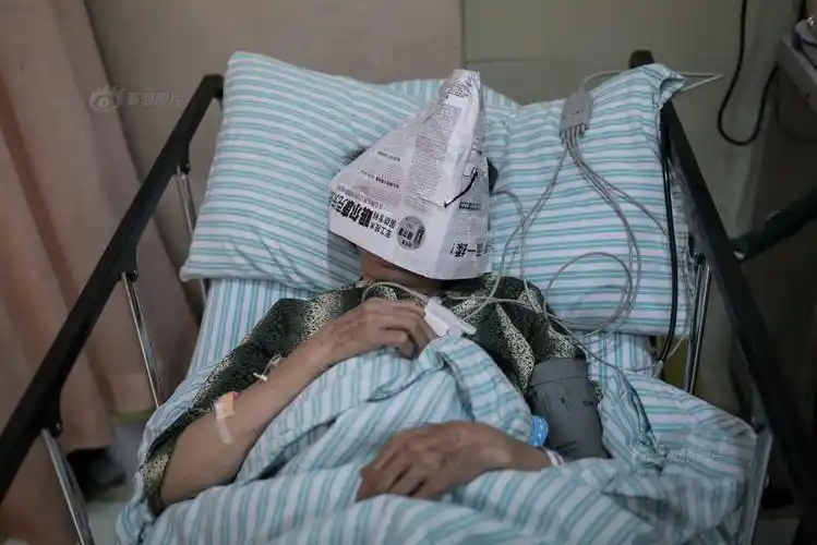 急诊抢救室,病床上一位病人的脸部被家属盖上报纸,以遮挡灯光便于