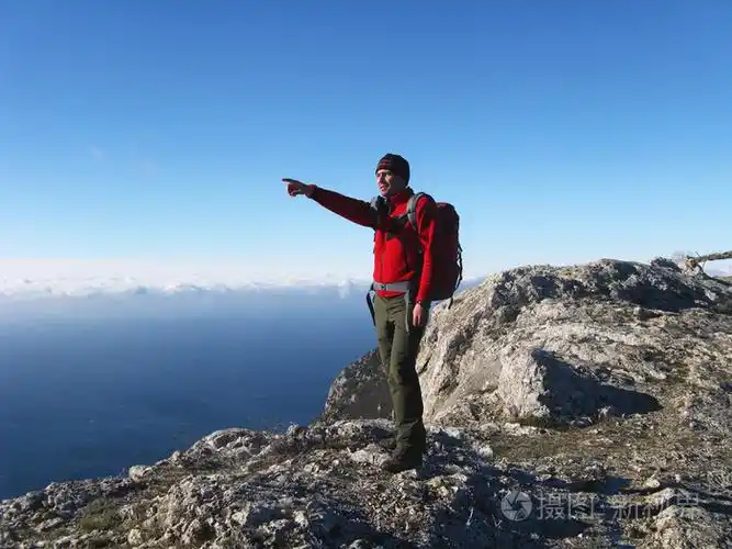 一名男子站在悬崖上看着大海在山与海的背景下