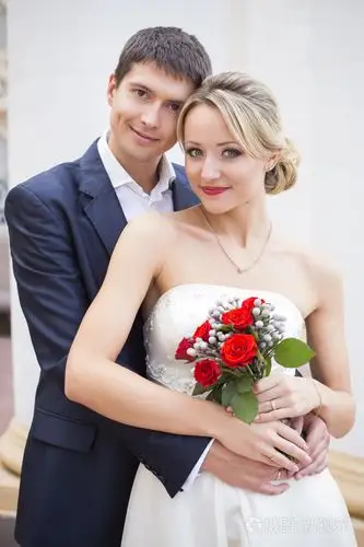 照片 接吻的结婚礼服的年轻夫妇.新娘紧握着红玫瑰花束.jpg