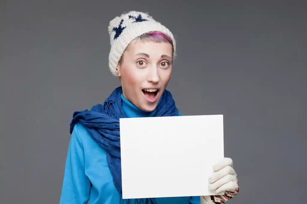 年轻开朗的女孩,在灰色的背景上举牌子