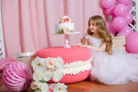 金发碧眼的小女孩庆祝生日快乐党与玫瑰装饰, 气球和蛋糕照片