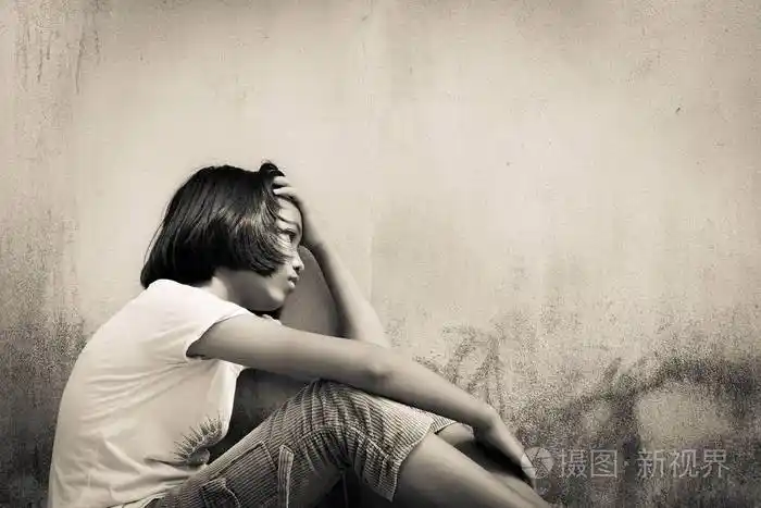 亚洲女孩伤心独自一人坐在白色熊老墙附近