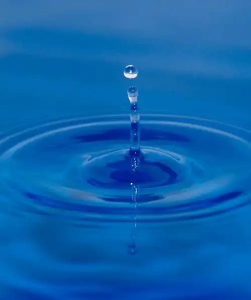 背景,一滴水落在蓝色的水中