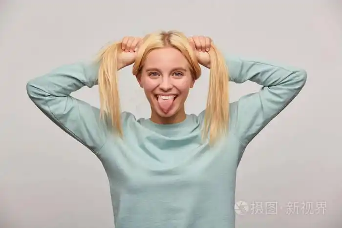 酷,搞笑,超级酷,超级酷,年轻的金发女孩在镜头上做鬼脸,舌头玩得很