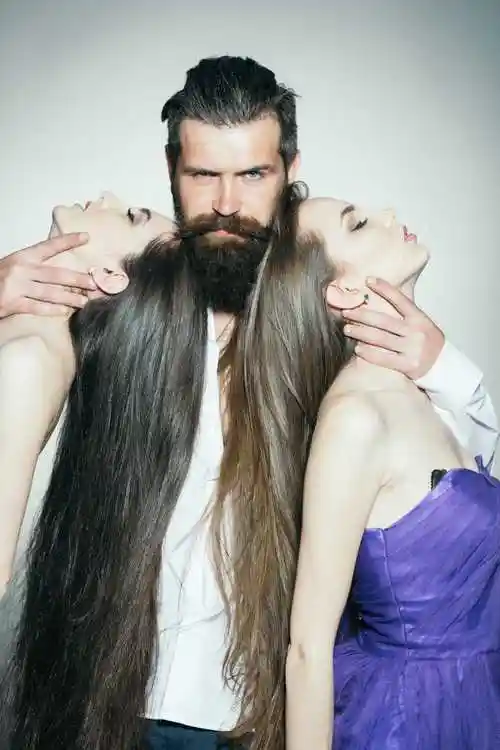 下的穿着白色衬衫的胡子帅气的男人和两个长头发的紫色女装的漂亮女人