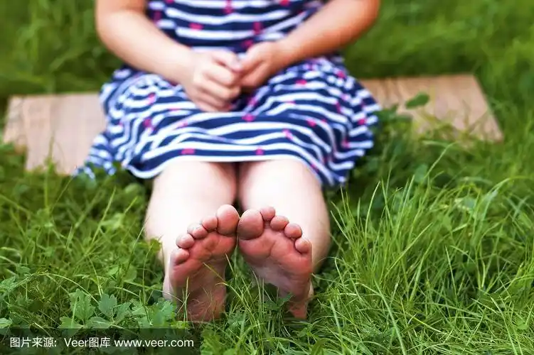 小女孩的脚在绿色的草地上的特写