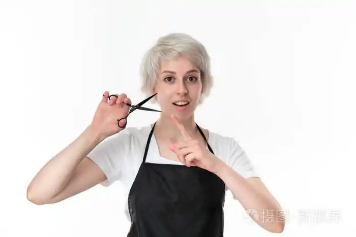 漂亮的理发师穿着白色t恤和黑色围裙,手持黑色剪刀准备工作,孤立地站