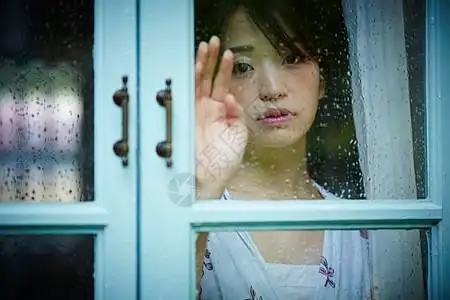 下雨天靠在窗边发呆的孤独女性图片素材